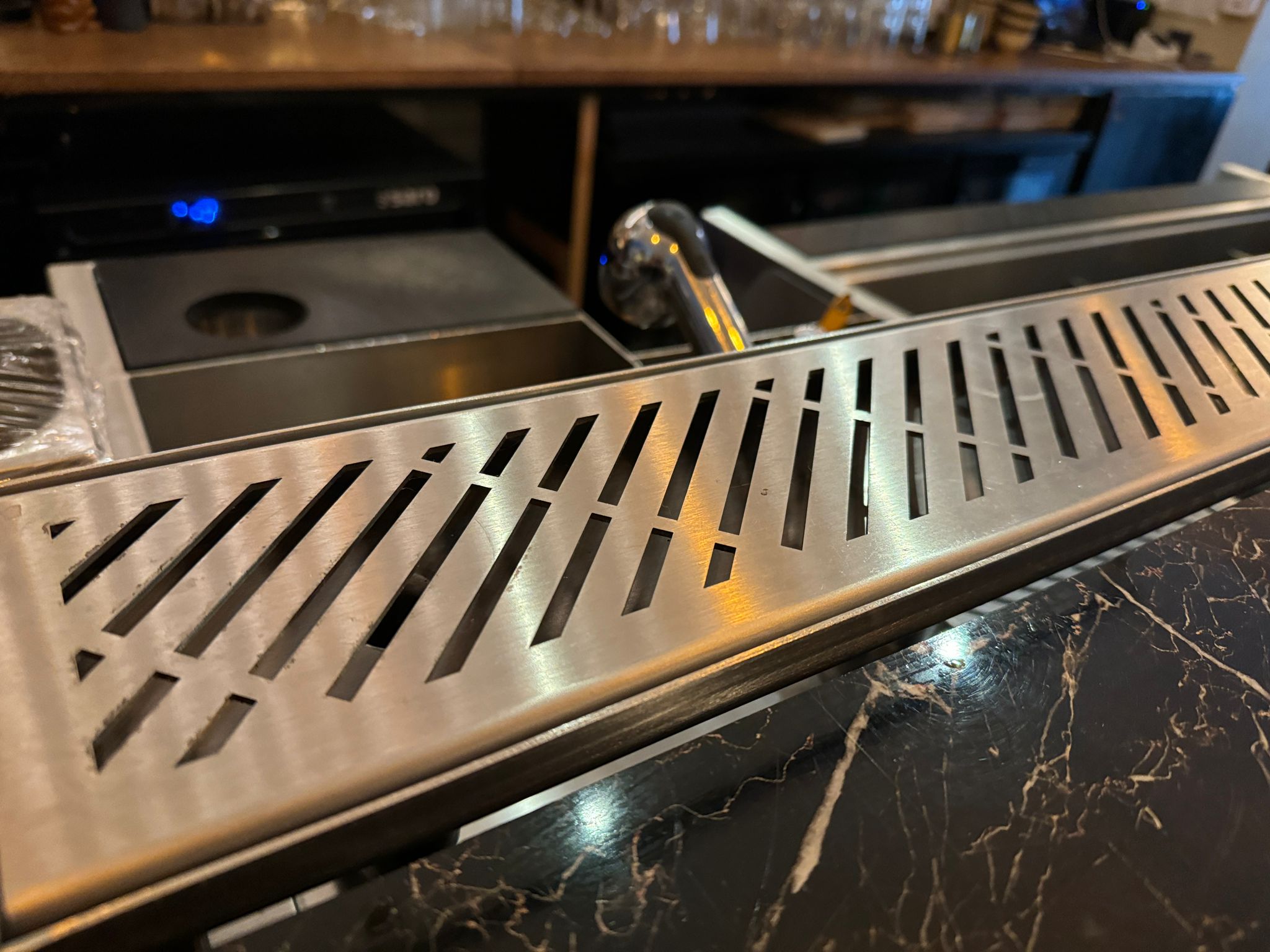 Commercial drink rail installed on stainless steel bar setup